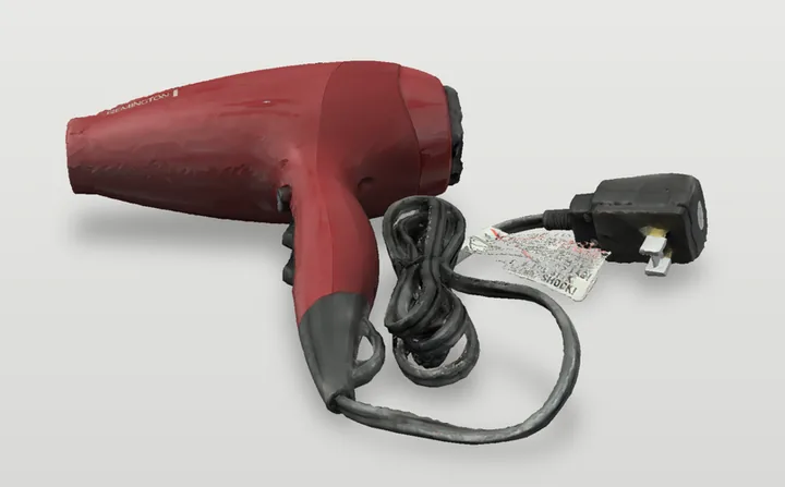 Photo of a red hair dryer with its cord and plug, lying on a table